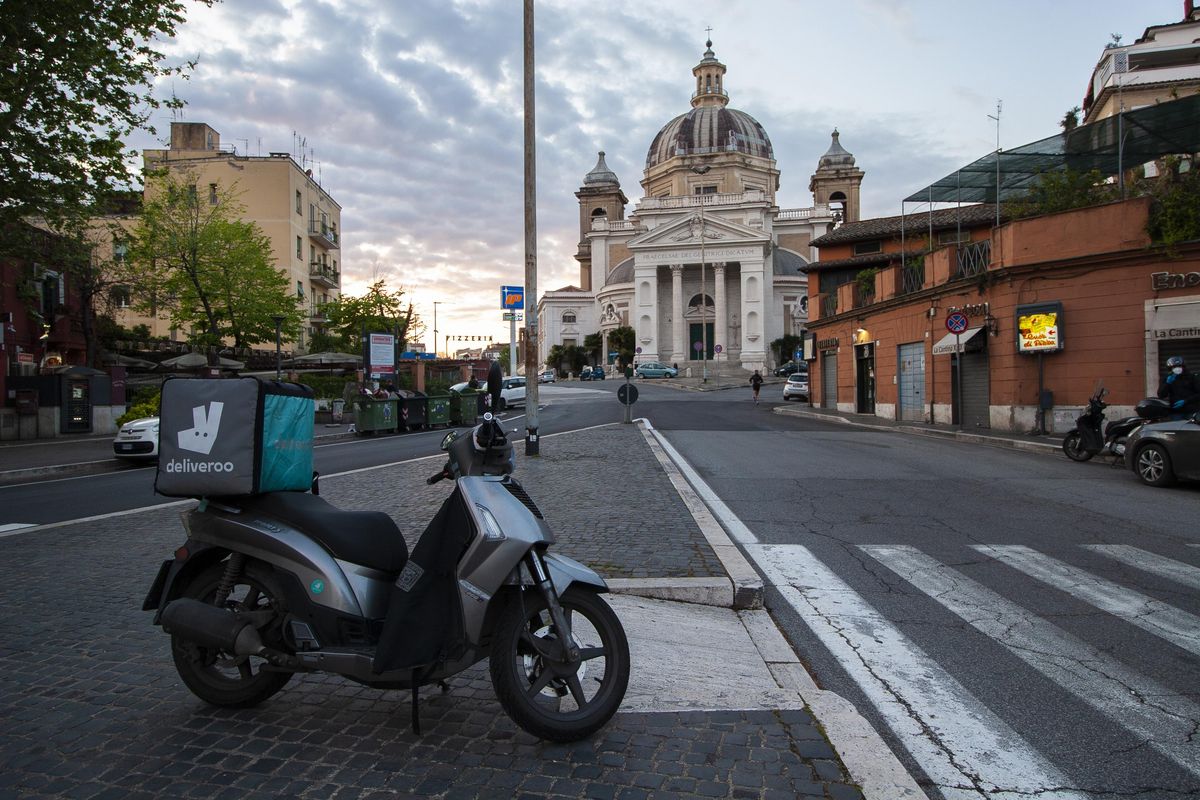 Food delivery vehicles make up much of the traffic on the streets. A driver picks up an order in the Ponte Milvio neighborhood of Rome, Italy, on Thursday. (Liz Mozzi / For The Spokesman-Review)