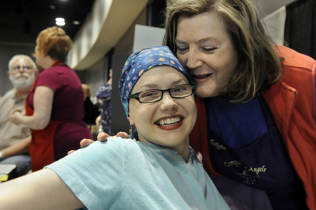 Heather McDonnell gets a hug from Tatjana Dorsch after Dorsch applied therapeutic essential oils to McDonnell’s neck at the Women’s Show in the Spokane Convention Center Saturday.  McDonnell has one chemotherapy breast cancer treatment left. (Dan Pelle)