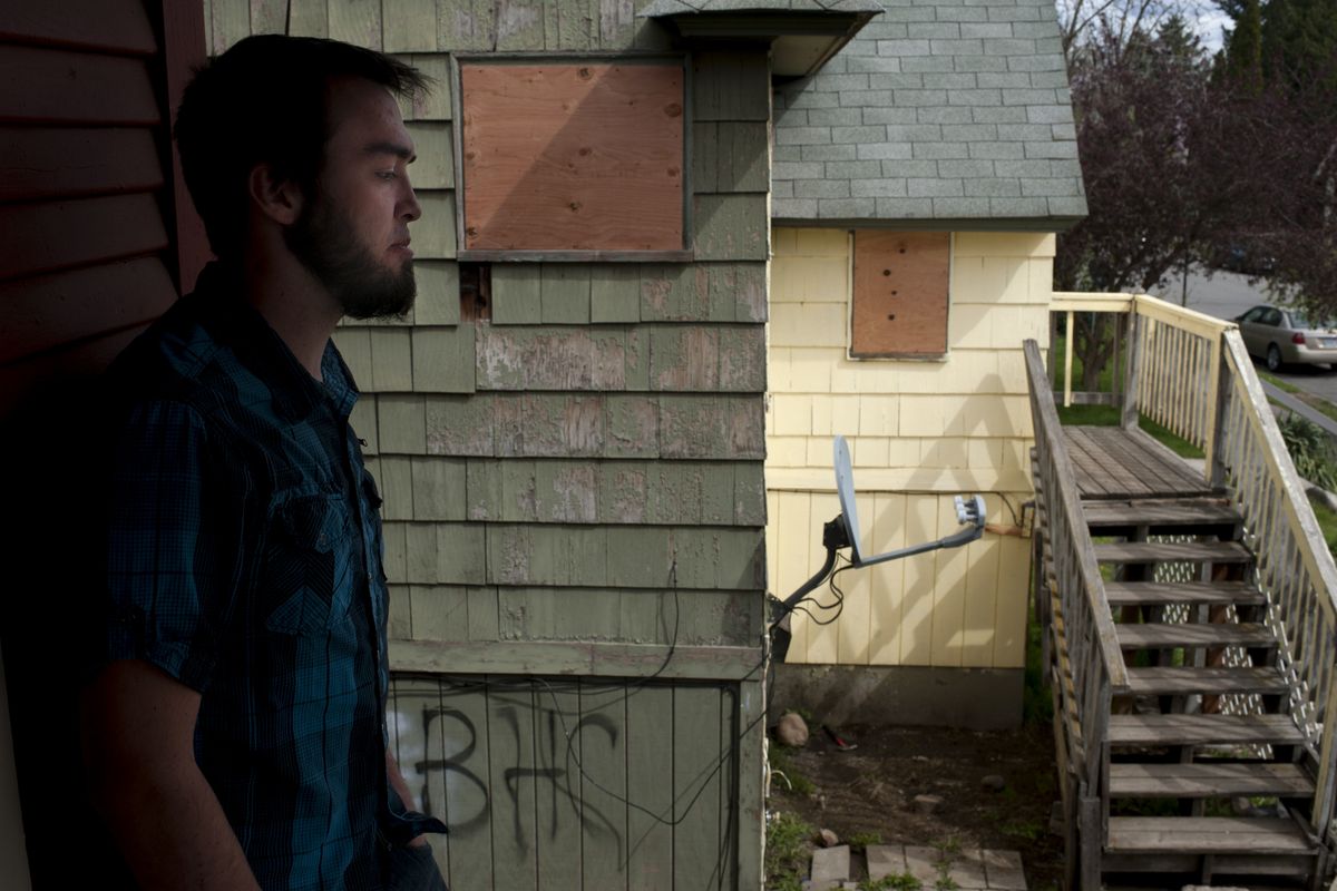 Alex Rehberg pauses as he reflects on his troublesome neighbors at 2332 W. College Ave. in Spokane’s West Central area. The owner of the longtime nuisance property, pictured in the background, was arrested Thursday for drug possession, and the home was boarded up. (Tyler Tjomsland)