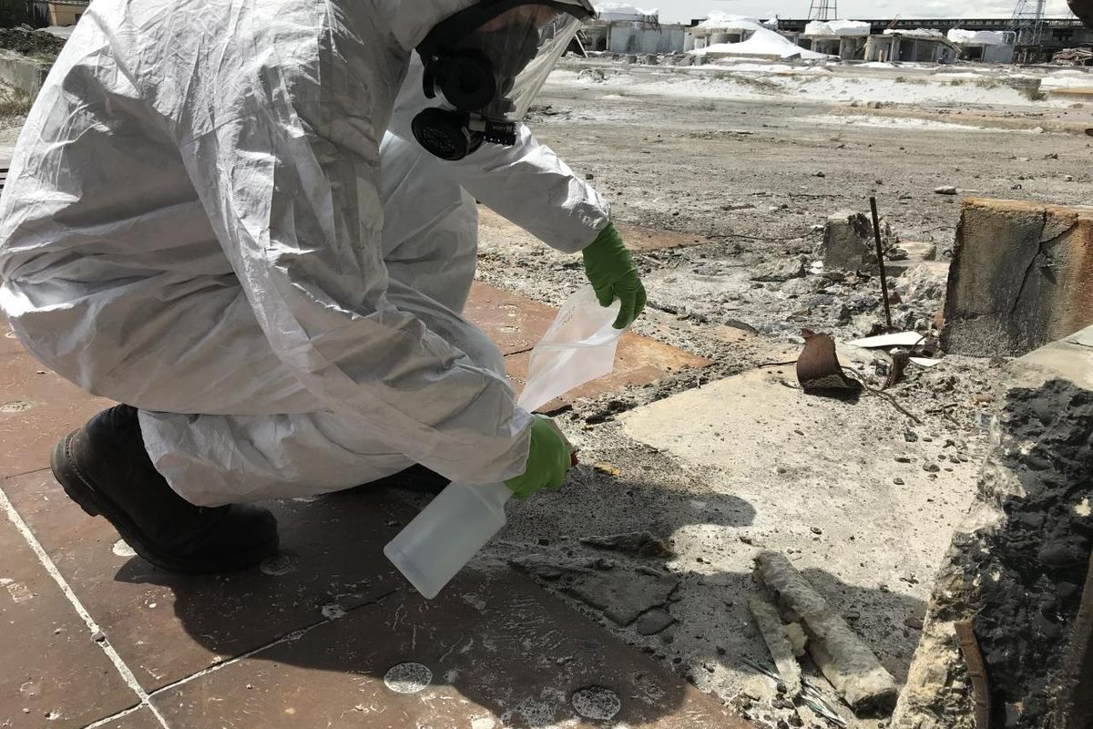 A worker samples materials in search of asbestos ahead of planned environmental cleanup at the former Kaiser Aluminum smelter site near Mead in this photo taken in May 2019.  (Courtesy Environmental Protection Agency)