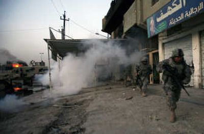 
U.S. Army soldiers  use smoke to take cover from snipers as they make their way to their vehicles from a patrol base in the Shiite enclave of Sadr City in Baghdad on Monday. Associated Press
 (Associated Press / The Spokesman-Review)
