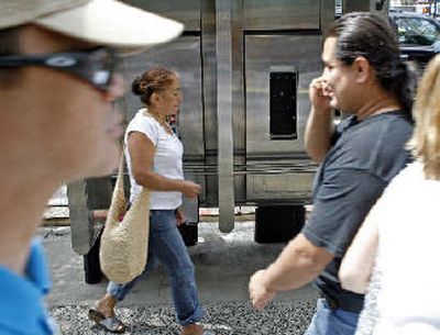 
Pedestrians, some talking on cell phones, walk past a stand of broken pay phones in New York. 
 (Associated Press / The Spokesman-Review)