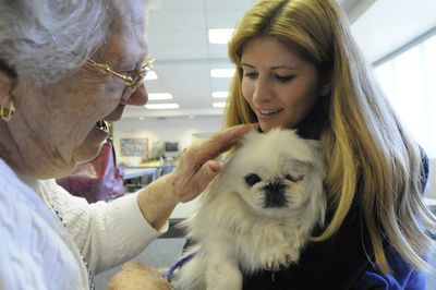 Ann Franek, left, greets Muppy, a one-eyed Pekingese dog held by Kathy Armstrong  at the East Central Community Center on Wednesday.  (Jesse Tinsley / The Spokesman-Review)