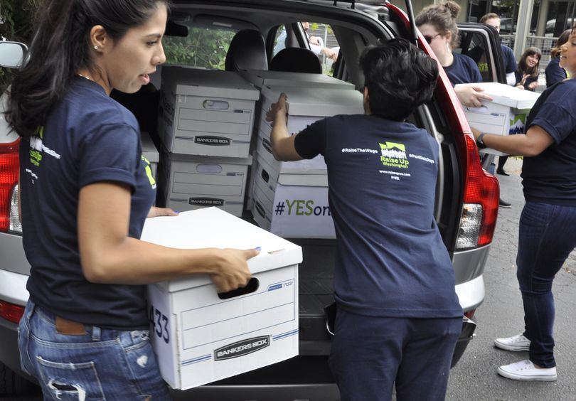 OLYMPIA -- Volunteers for Initiative 1433, which would raise the state minimum wage and guarantee paid sick leave for many workers in Washington, deliver boxes of signed petitions to the state Elections Office Wednesday morning. (Jim Camden/The Spokesman-Review)