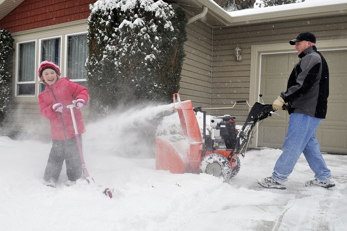 Shawn Hobbs blows snow on his daughter Sarah, 5, after she refused to move out of the way Wednesday in Spokane Valley. (Jesse Tinsley)
