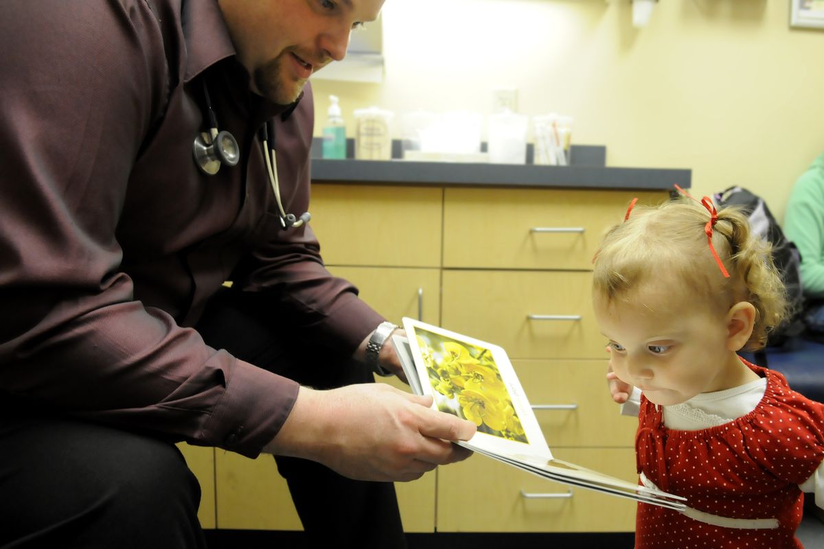 Dr. Daniel Moorman shows Natalie Denham pictures in a book. Through Reach Out and Read, Moorman and other doctors provide books to kids. (Jesse Tinsley)