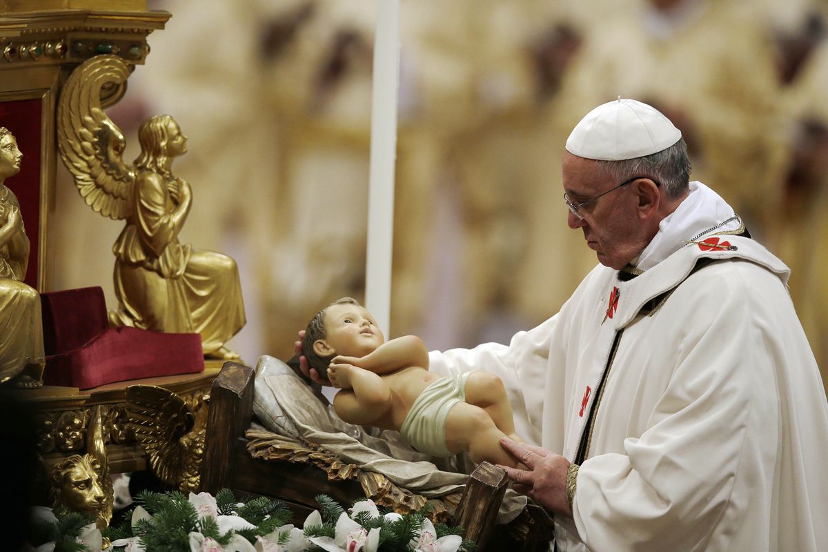 Pope Francis holds a statue of baby Jesus as he celebrates Christmas Eve Mass in St. Peter’s Basilica at the Vatican on Tuesday. (Associated Press)