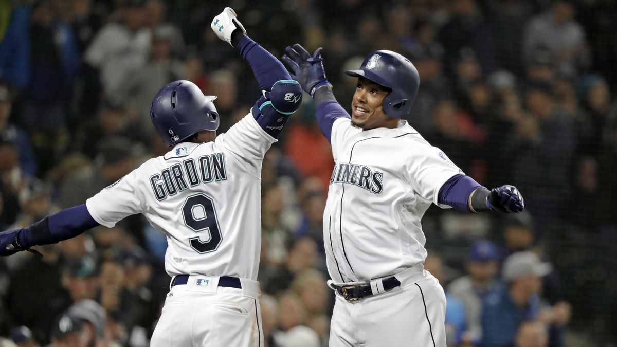 Seattle’s Jean Segura, right, is cheered by Dee Gordon after hitting a three-run home run against the Oakland Athletics in the second inning Saturday in Seattle. (Elaine Thompson / AP)