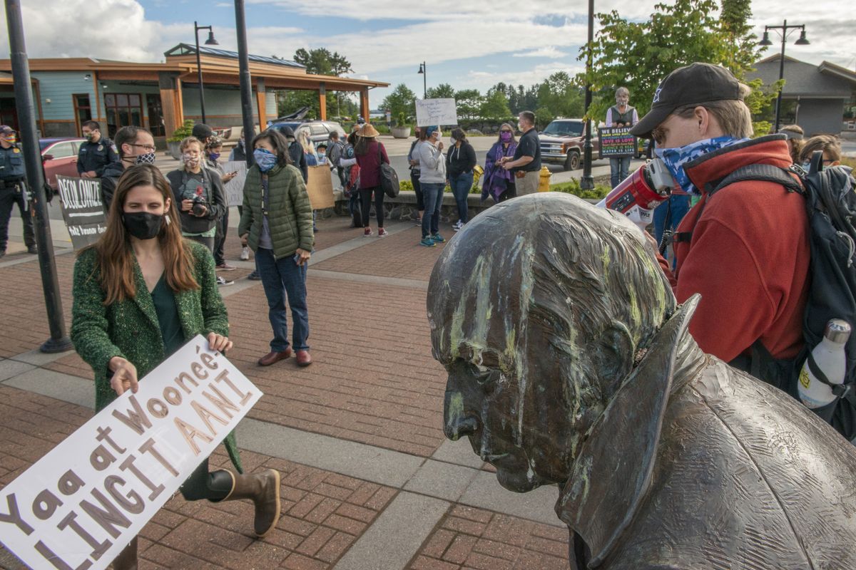 FILE - In this June 23, 2020, file photo, protesters gather near the statue of Russian colonialist Alexander Baranov in front of Harrigan Centennial Hall in Sitka, Alaska, just prior to a city Assembly meeting. The Sitka Assembly voted July 14 to relocate the statue to the Sitka Historical Society Museum inside the Harrigan Centennial Hall. Baranov, who founded the city in 1804 on a site already inhabited by Alaska Natives, was known as a brutal colonialist who murdered and enslaved Alaska Native people before the United States purchased Alaska from Russia in 1867.  (James Poulson)