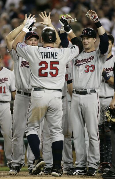 Michael Cuddyer, left, and Justin Morneau, right, greet Twins teammate Jim Thome after his milestone home run. (Associated Press)