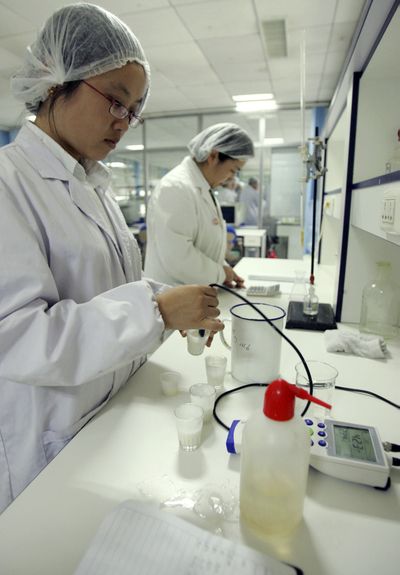 Technicians test milk samples Saturday at a Beijing laboratory.  (Associated Press / The Spokesman-Review)