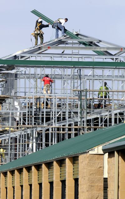 Work crews attach sheets of roofing to a corner building section of the new addition at Self Storage on North Foothills Drive in Spokane.  (Dan Pelle / The Spokesman-Review)