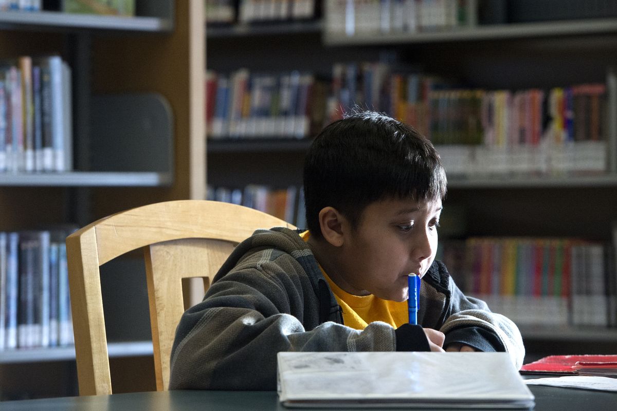 Daniel DeVera, a seventh-grader from Shaw Middle School, works on his homework at the Hillyard Library on Feb. 6. The library now has longer hours. (Jesse Tinsley)