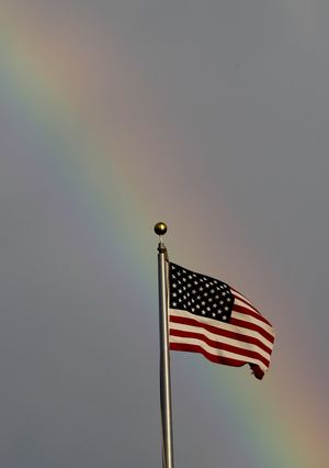 A rainbow from a morning thunderstorm paints the background for an American flag in Lawrence, Kan., Tuesday, Aug. 16, 2011. (Orlin Wagner / Associated Press)