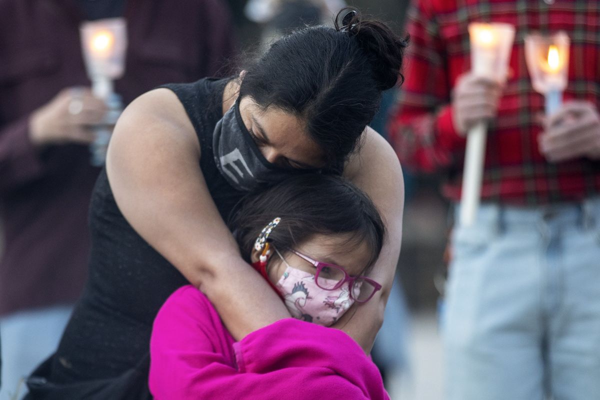 A mother hugs her daughter during a vigil in Toronto on Sunday May 30, 2021, for the 215 Indigenous children, whose remains were uncovered on the grounds of a former residential school near Kamloops, British Columbia. The discovery of a mass grave was announced late on Thursday by the Tk