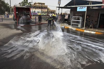 Firemen wash down street after three U.S. soldiers and four Iraqis were killed in a blast in Baghdad on Thursday. (Associated Press / The Spokesman-Review)