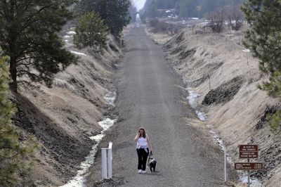 Michele Deyette and her dog Atticus  stroll  along the Columbia Plateau Trail  in Cheney on Thursday. This summer, federal stimulus funds will begin paving the Fish Lake Trail, which will connect Spokane and nearby Fish Lake.  The Fish Lake Trail is managed by the cities of Spokane and Cheney.  (Jesse Tinsley / The Spokesman-Review)