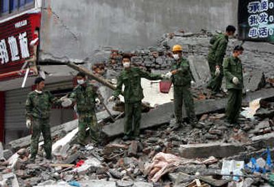 
Paramilitary police officers form a chain to remove chunks of concrete as they search for bodies in the rubble of a collapsed building in Dujiangyan, in China's southwest Sichuan province Wednesday. The official death toll from Monday's earthquake reached almost 15,000 Wednesday. Associated Press photos
 (Associated Press photos / The Spokesman-Review)