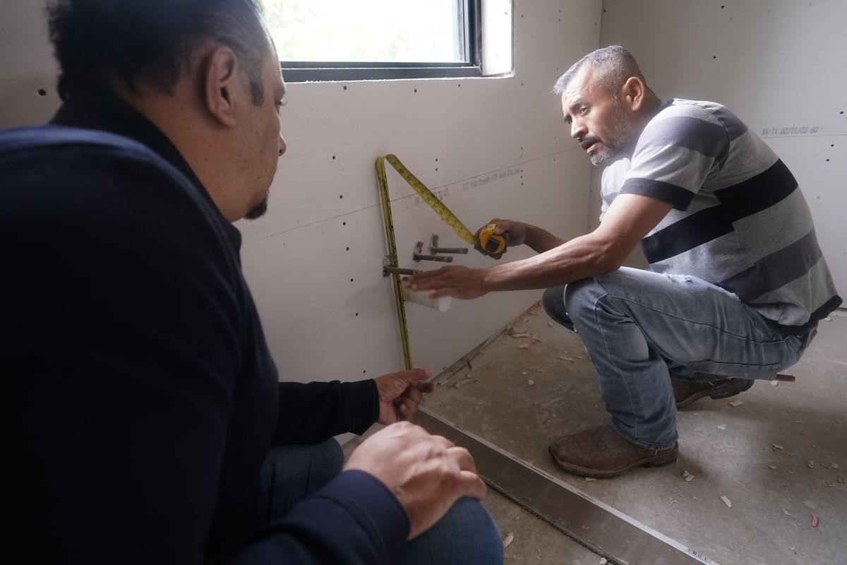 Tile subcontractor Horacio Gomez, right, originally from the Mexican state of Michoacan, measures and talks with homebuilder Joshua Correa about plans at a custom home under construction in Plano, Texas, Tuesday, May 3, 2022. There are an estimated 2 million fewer immigrants than expected in the United States, helping fuel a desperate scramble for workers in many sectors, from meatpacking to homebuilding, that are also contributing to shortages and price increases.  (LM Otero)