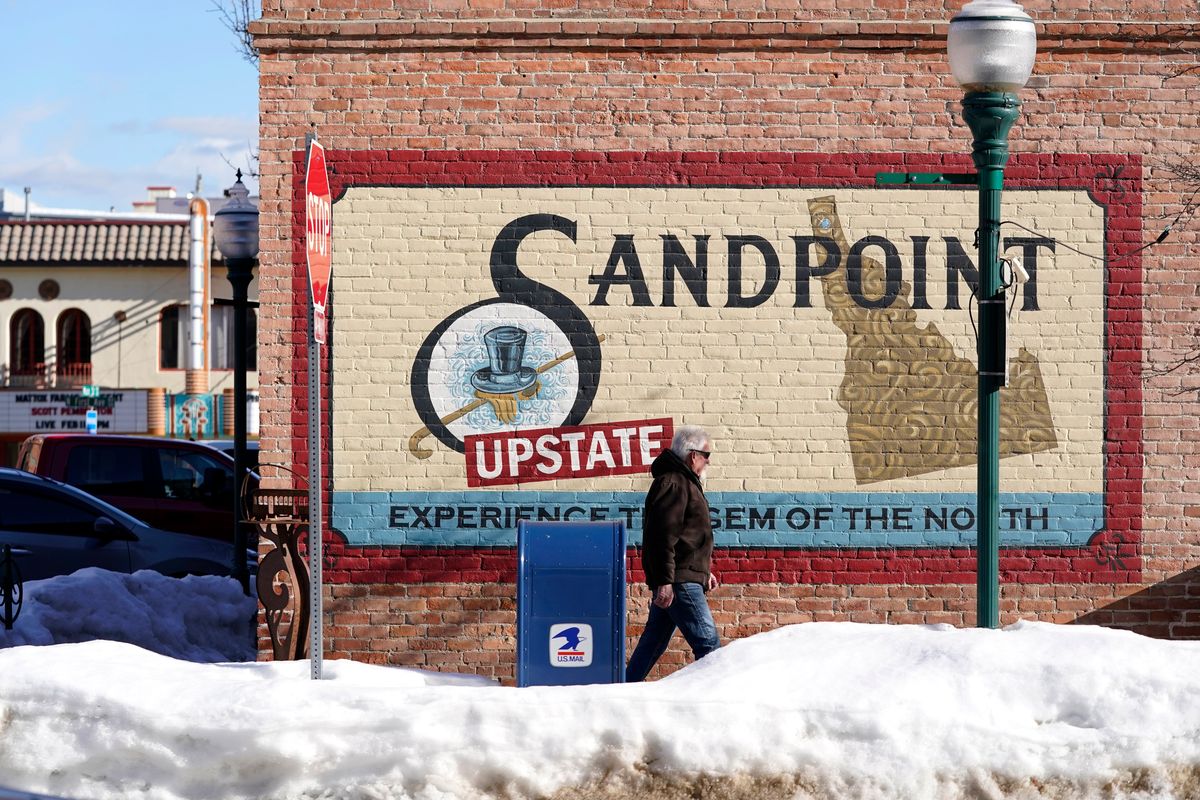 A pedestrian walks past a mural, Monday, Feb. 7, 2022, in downtown Sandpoint, Idaho. The Mayor of Sandpoint and many residents worry that the trend of a growing number of real estate companies advertising to conservatives that they can help people move out of liberal bastions like Seattle and San Francisco and find homes in places like rural Idaho is not good for their community.  (Ted S. Warren)