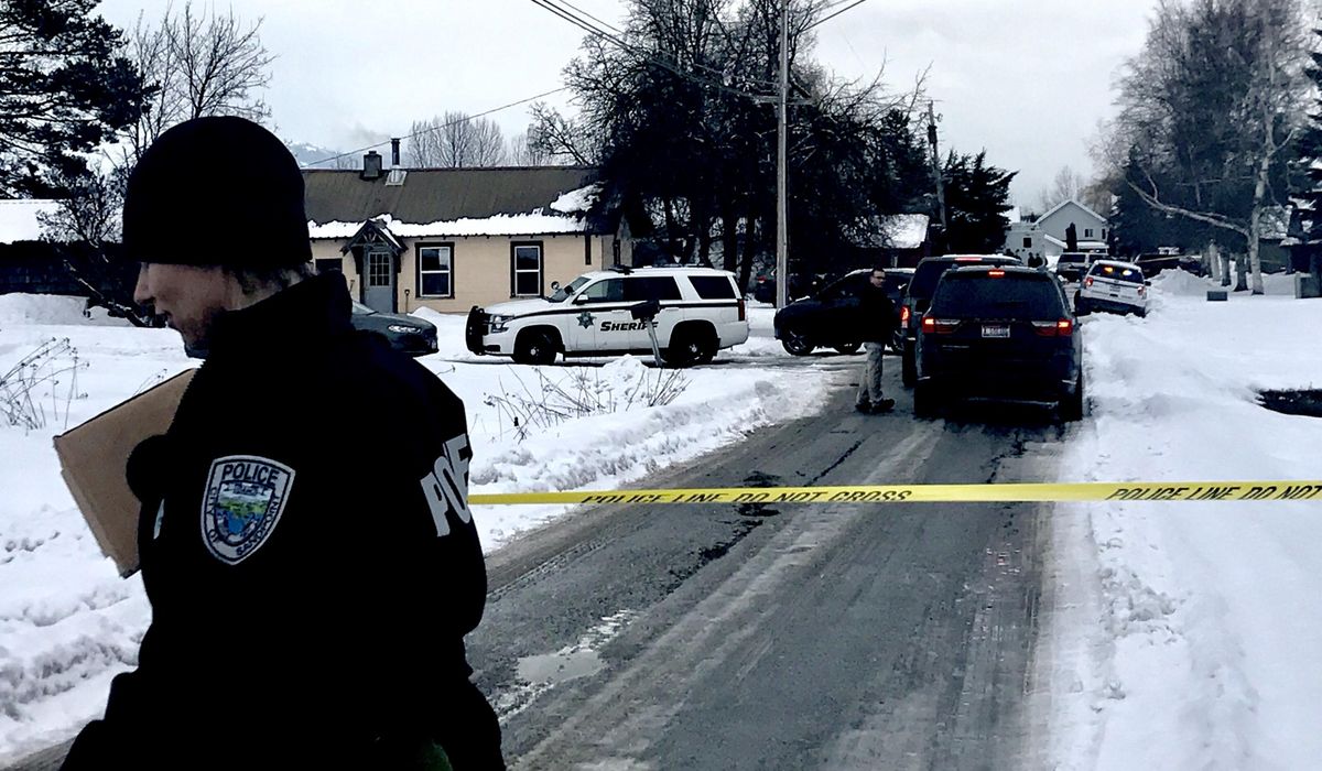 A Sandpoint police officer tapes off  a crime scene on Ridley Village Road on Monday, near the residence where two Sandpoint police officers were shot. (Kathy Plonka / The Spokesman-Review)