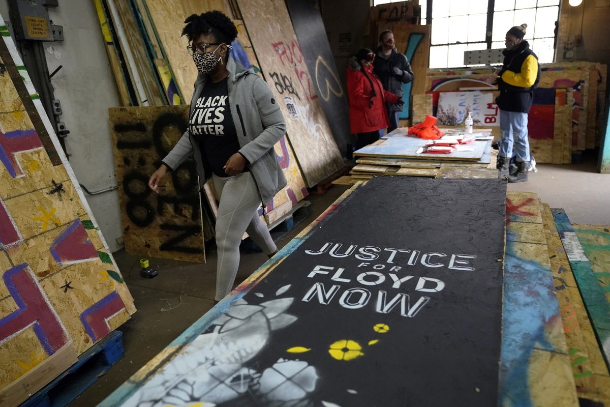 Leesa Kelly, left, walks past plywood mural boards as she and Kenda Zellner-Smith, background right, and volunteers meet at a warehouse on Saturday in Minneapolis to organize them.  (Jim Mone)