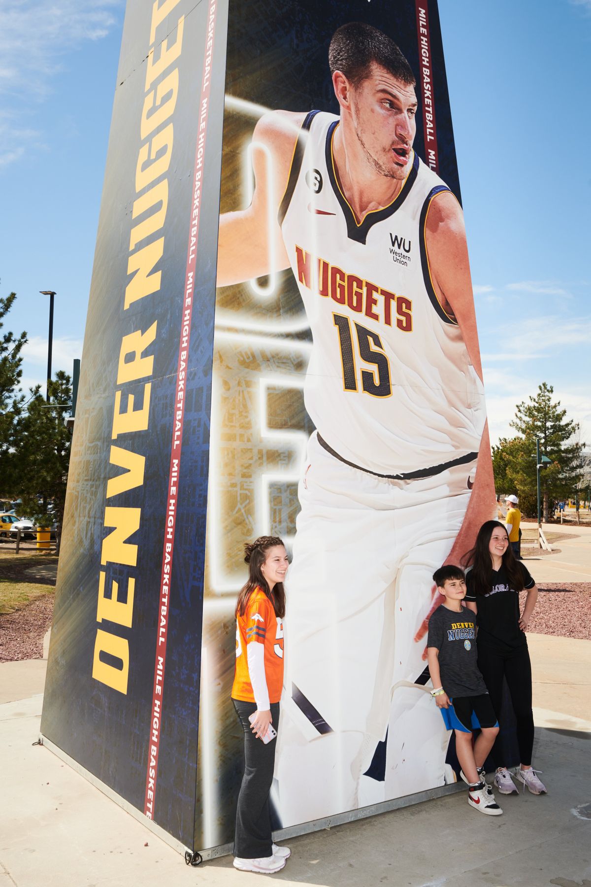 Youths take photos with a huge poster of the Nuggets superstar Nikoa Jokić outside Ball Arena in Denver before a game versus the Sacramento Kings, on April 9, 2023.   (New York Times)