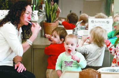 
Early-childhood specialist Julie Bostwick-Cosby leads, from left, Dorina Seremet, Brooklyn Sacherer and Steven Allison-Derrick, through a tooth-brushing session in the Early Head Start Infant/Toddler classroom at the West Central Community Center.
 (Dan Pelle / The Spokesman-Review)