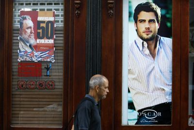 A man walks past a poster showing Cuba’s leader Fidel Castro and an advertisement of fashion designer Oscar de la Renta in Havana on Tuesday. Cuba will celebrate the 50th anniversary of the 1959 revolution today.  (Associated Press / The Spokesman-Review)