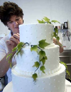 
Diana Tesdal decorates a wedding cake with gum-paste ivy vines at the Happy Cake Co. in Spokane Valley. 
 (Liz Kishimoto / The Spokesman-Review)