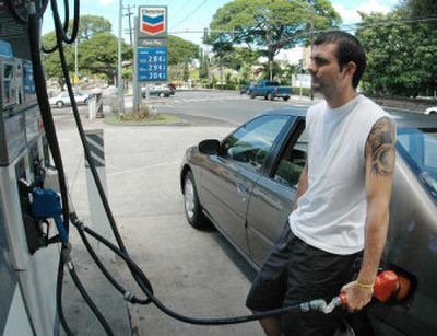 
Chris Cusmano fills his car's gas tank in Honolulu Wednesday. In an effort to gain some control over what motorists pay at the pump, the state Public Utilities Commission set the nation's first state caps on the wholesale price of gasoline. 
 (Associated Press / The Spokesman-Review)