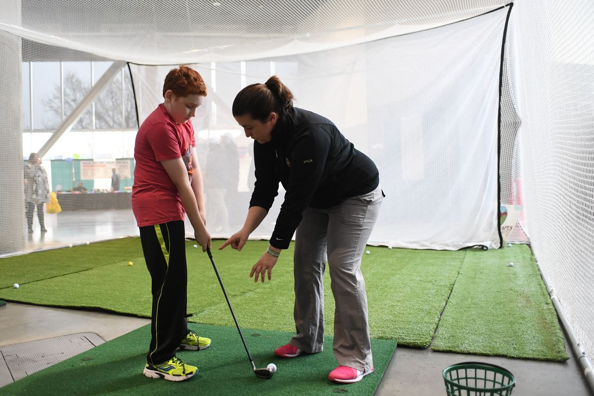 Indian Canyon assistant pro Michelle Grafos gives Gabriel Mitchell, 10, some basic pointers at a booth at the 2017 Spokane Golf and Travel Show. (Jesse Tinsley / The Spokesman-Review)