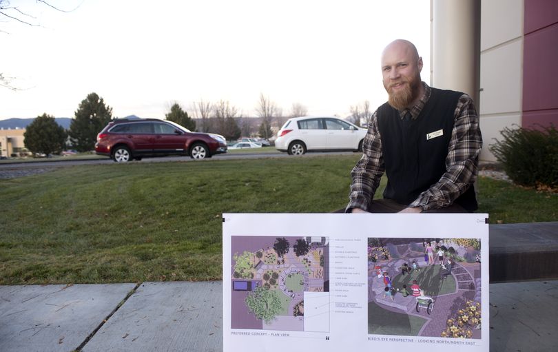 Liberty Lake librarian Dan Pringle sits outside the library Monday with a landscape architect’s plans to turn the land behind him into an outdoor reading garden. The work will begin next spring. (Jesse Tinsley)