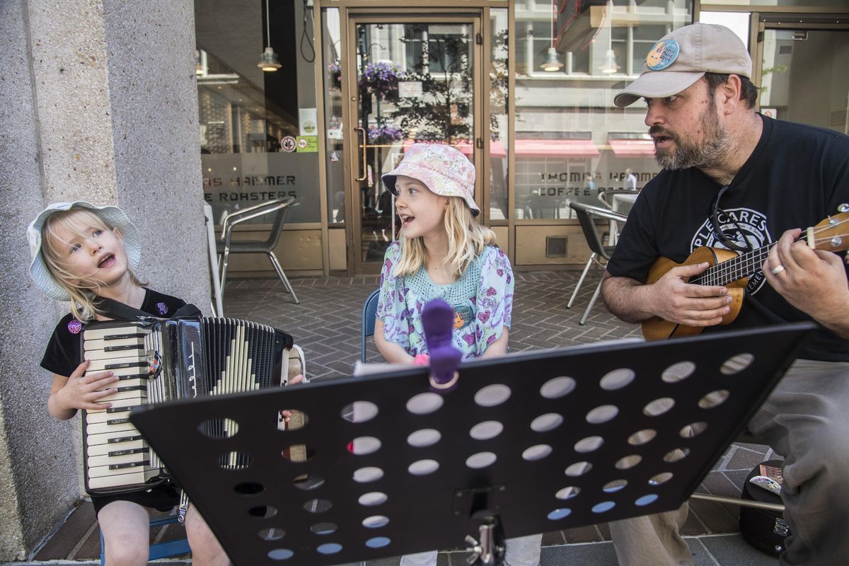 Ivy, 6, Neilia, 8, and their father, Carey Eyer, sing and play at Street Music Week, June 12, 2017, in downtown Spokane, Wash. (Dan Pelle / The Spokesman-Review)
