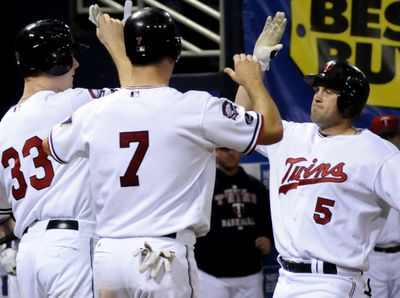 Twins Justin Morneau, left, and Joe Mauer, center, greet Michael Cuddyer, right, after his homer. All three went long Saturday. (Associated Press / The Spokesman-Review)
