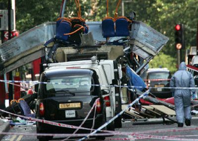 
A forensic officer walks next to wreckage of a double-decker bus with its top blown off and damaged cars scattered on the road at Tavistock Square in central London Thursday. 
 (Associated Press / The Spokesman-Review)