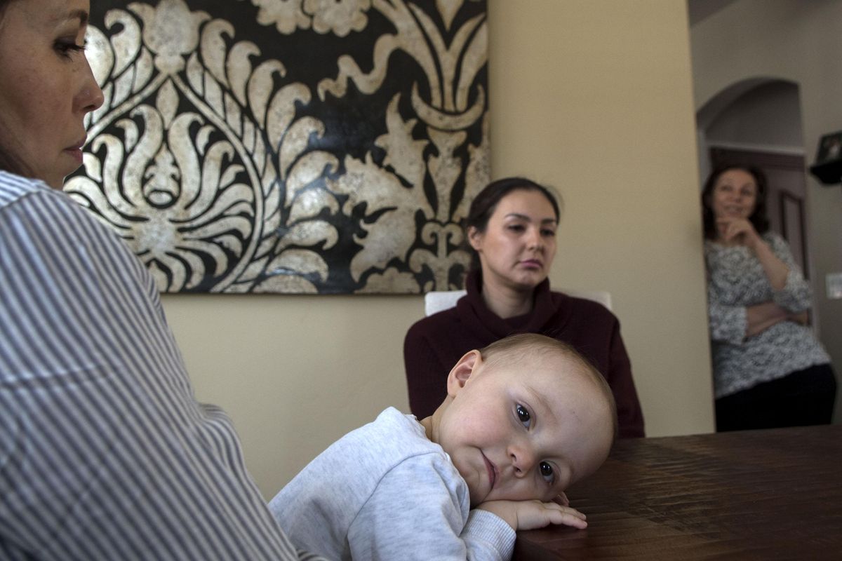 Leah Zhukov, 17 months old, sits on her mother, Aygul Bekjanov’s lap, while her aunt Kamila Bekjanov, center and her grandmother Nina Bekjanov, far right talk about the release of her grandfather Muhammad Bekjanov, an Uzbek newspaper editor. They were interviewed at their home in Spokane Valley on Wednesday, Mar. 2, 2017. (Kathy Plonka / The Spokesman-Review)