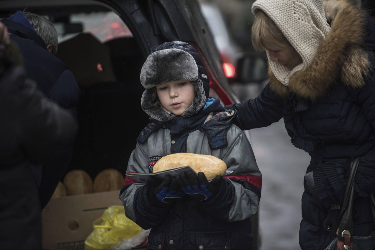 A boy carries a loaf of bread after receiving humanitarian aid in Avdiivka, Ukraine, Saturday, Feb. 4, 2017. (Evgeniy Maloletka / Associated Press)