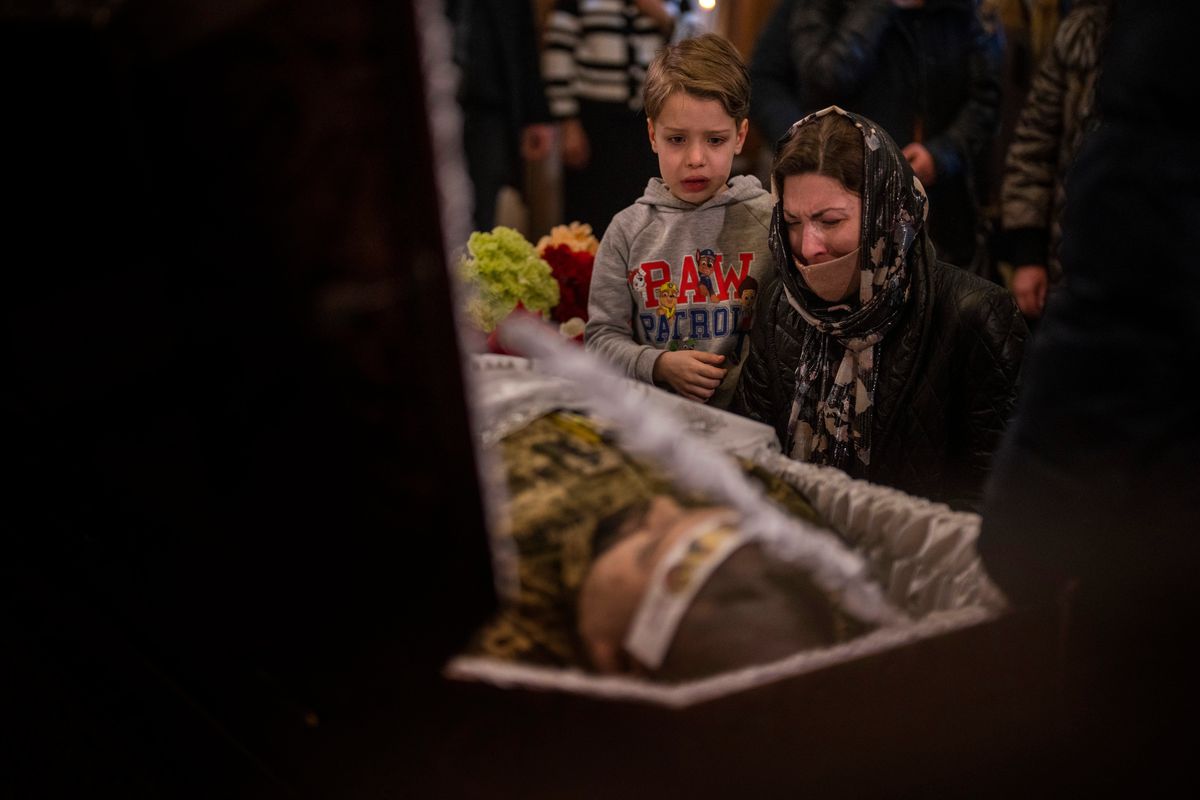 A woman and a boy react next to the body of Ukrainian Army captain Anton Sydorov, 35, killed in eastern Ukraine, during his funeral, in Kyiv, Ukraine, Tuesday, Feb. 22, 2022. Western leaders said Tuesday that Russian troops have moved into rebel-held areas in eastern Ukraine after President Vladimir Putin