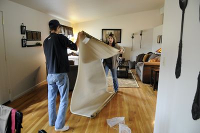 Brian Feldhusen and Rita Hollis unroll a rug in the model home at Windsor Crossing. There are 226 former military homes being refurbished on the Geiger Heights site. (Dan Pelle / The Spokesman-Review)