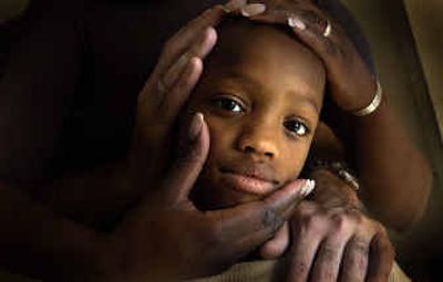 
Terrence McKinney, 10, of Davenport is held by his parents, Kitara and Ross McClure, in their Davenport home.  Claims of race discrimination against the boy in school have sparked a civil rights investigation. 
 (Brian Plonka / The Spokesman-Review)