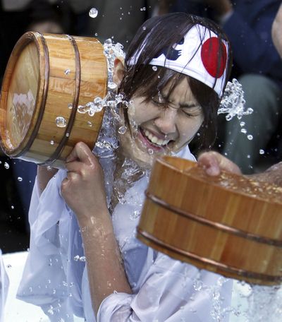 One of well-wishers using wooden tubs splashes cold water onto herself during an annual cold-endurance festival at the Kanda Myojin Shinto shrine in Tokyo, Saturday morning, Jan. 9, 2010. (Koji Sasahara / Associated Press)