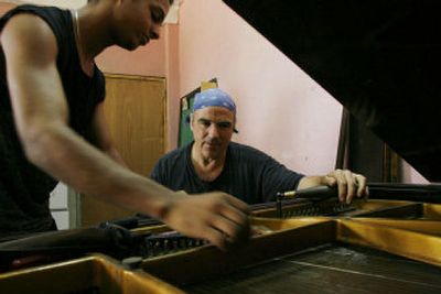 
American piano tuner Benjamin Treuhaft, right, repairs a piano accompanied by Yoellis Lubin, a recent graduate from a piano tuning school, at Cuba's Superior Art Institute in Havana. 
 (Associated Press / The Spokesman-Review)