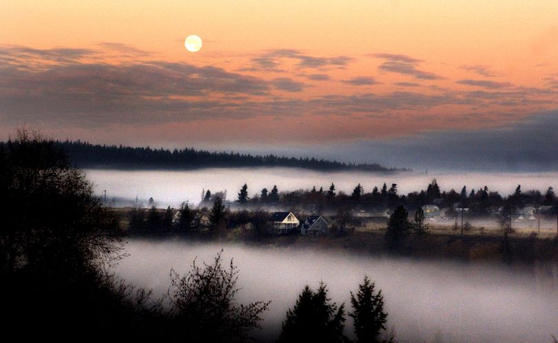At sunrise, the moon heads for the western  horizon while morning fog that had settled over the Spokane River in Peaceful Valley begins to rise with the sun in 2002. (Colin Mulvany / The Spokesman-Review)
