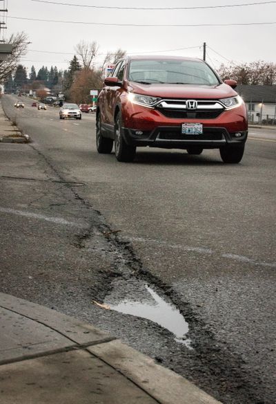 A vehicle passes an area with surface deterioration at Pines and Fourth Avenue, on Wednesday, Dec. 9, 2020 in Spokane Valley, Wash.  (Libby Kamrowski/ THE SPOKESMAN-REVIEW)