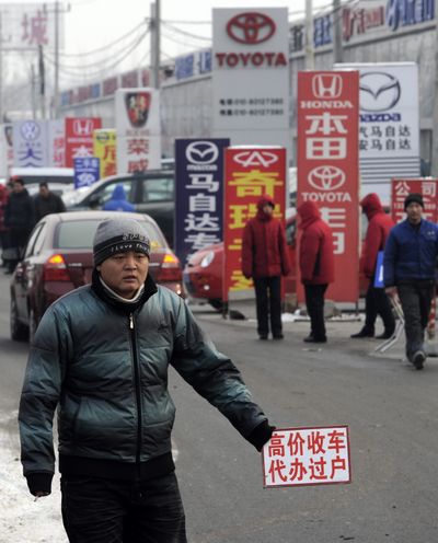 A man holds a sign  reading “offering high price for secondhand car” to customers entering  an auto market in Beijing on Friday. Vehicle sales in China in 2009 were up about 45 percent from 2008.  (Associated Press)