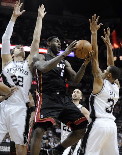 Miami Heat forward LeBron James drives between San Antonio Spurs' Tiago Splitter (22) and George Hill. (Associated Press)