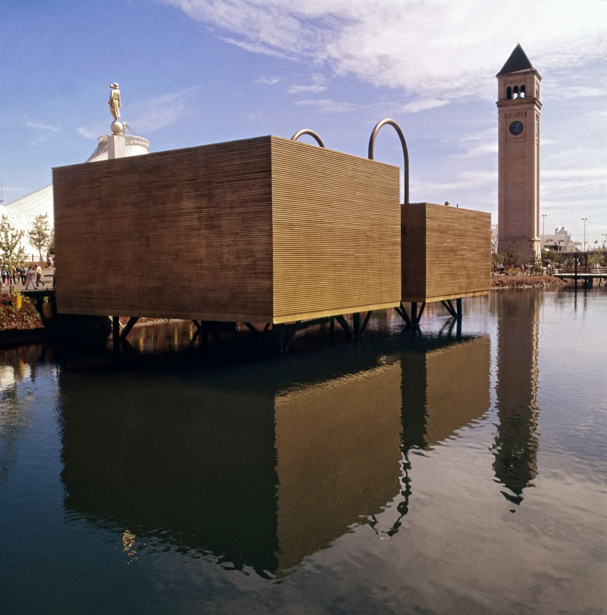 1974: The Book of Mormon Pavilion, built on pilings in the Spokane River, was one of two religious pavilions at Expo ’74. The Great Northern Clocktower, right, and the U.S. Pavilion, behind, are shown around the grounds of the fair on July 19, 1974. The 40-by-80-foot building, designed by Molander Associates, was intended to resemble the stack of golden plates that church founder Joseph Smith said he found containing the text of the Book of Mormon.  (Spokesman-Review photo archives)