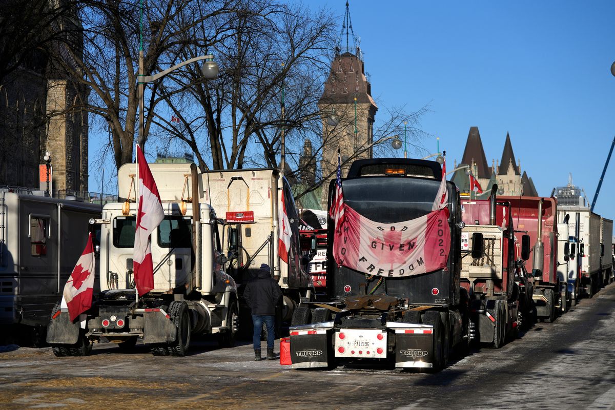 A person walks among trucks as Wellington Street is lined with trucks once again after city officials negotiated to move some trucks towards Parliament and away from downtown residences, on the 18th day of a protest against COVID-19 measures that has grown into a broader anti-government protest, in Ottawa, on Monday, Feb. 14, 2022. (Justin Tang)
