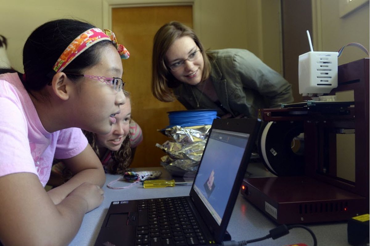 Helen Gao, 12, left, watches a 3-D printer make a simple plastic figurine with Morgan Herrington, center, and Hayley Gower, right, high school mentors, at a science camp at Sacajawea Middle School on Wednesday, July 23, 2014. Careers in science, technology, engineering and math are dominated by males, but there are many ways girls are introduced to science, including summer camps like those at Sacajawea.  Gao was the only one to sign up for the 3-D printing camp. (Jesse Tinsley)